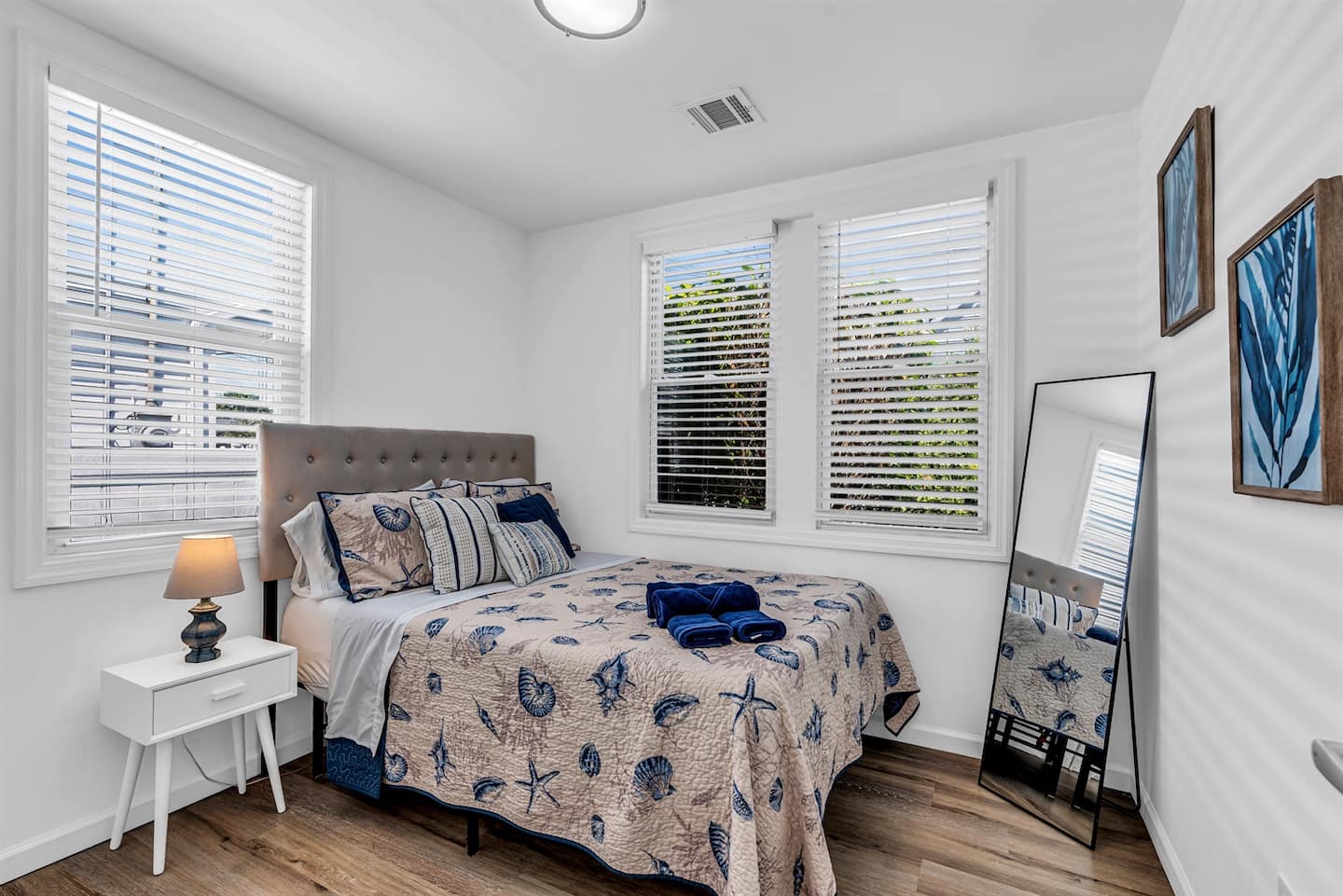 Bedroom two with a full bed, grey tufted headboard and shell-print bedding