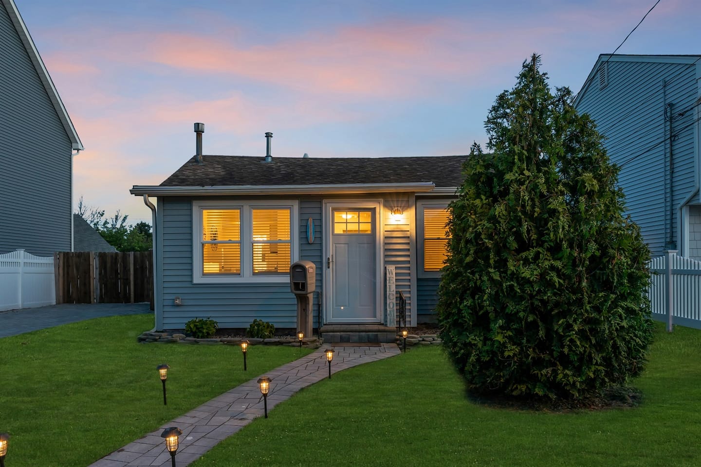 Cozy coastal cottage with a warmly lit path and inviting evening glow.