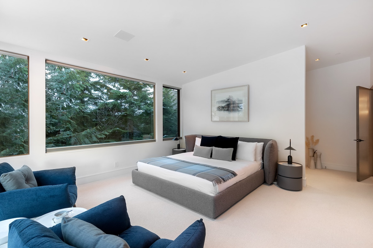 - Bedroom 1 – King room with expansive windows framing calm forest views
- Soft tones, cozy bedding, and modern seating create a soothing retreat
- A bright peaceful space designed for restful nights and relaxing stays
