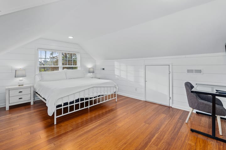 سرير بحجم كبير ومنطقة جلوس للعمل وتلفزيون مثبت على الحائط