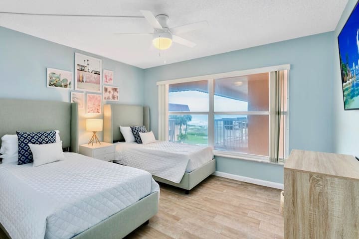Habitación de invitados con dos camas individuales, vista parcial al mar y TV de pantalla grande