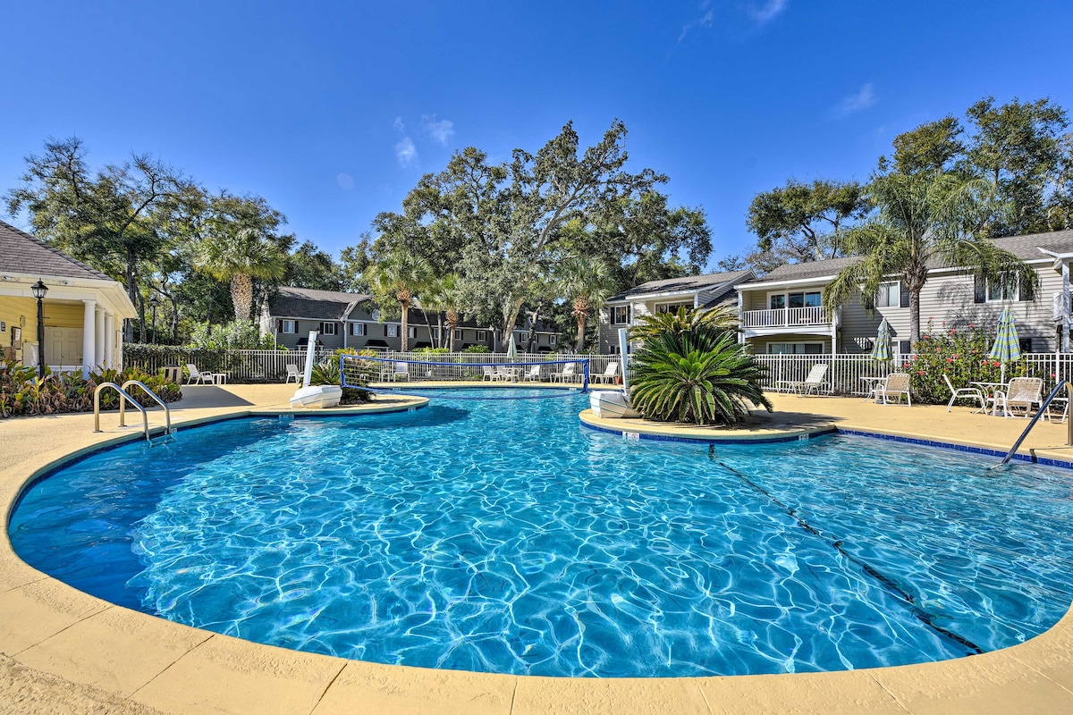 A clear blue pool is surrounded by a spacious patio and lush landscaping. Sunlight reflects on the water’s surface, creating a calming environment. Lounge chairs are placed around the pool area, offering ample space for relaxation.
