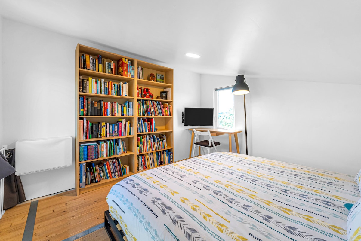 Dormitorio loft con cama King, biblioteca, escritorio y TV inteligente.