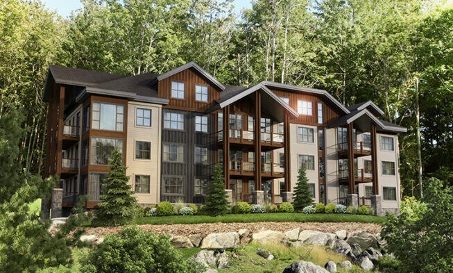 The exterior of the property is captured amidst a natural landscape, showcasing a multi-story building with a blend of wood and stone. Balconies are visible on each level, surrounded by lush greenery and carefully arranged landscaping that enhances the inviting character of the space.