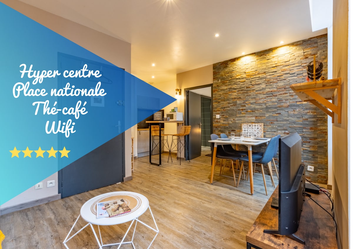 An open living area presents a combination of modern and rustic elements. Highlighted are a smart TV, a dining table with chairs, and a textured stone wall. Light wood flooring extends throughout, while a coffee table sits beside a cozy seating arrangement.
