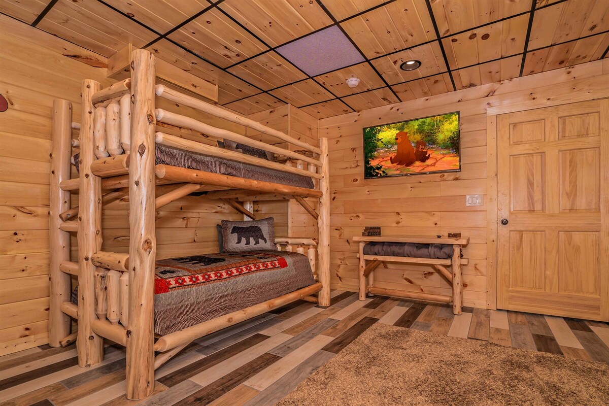 Soba s krevetima na kat na nižoj razini s rustikalnim drvenim krevetima na kat, udobnom posteljinom, TV-om na zidu i klupom za sjedenje. Odličan prostor za djecu ili dodatni prostor za spavanje, udaljen od glavnih stambenih prostora kako bi se osigurao miran odmor.
