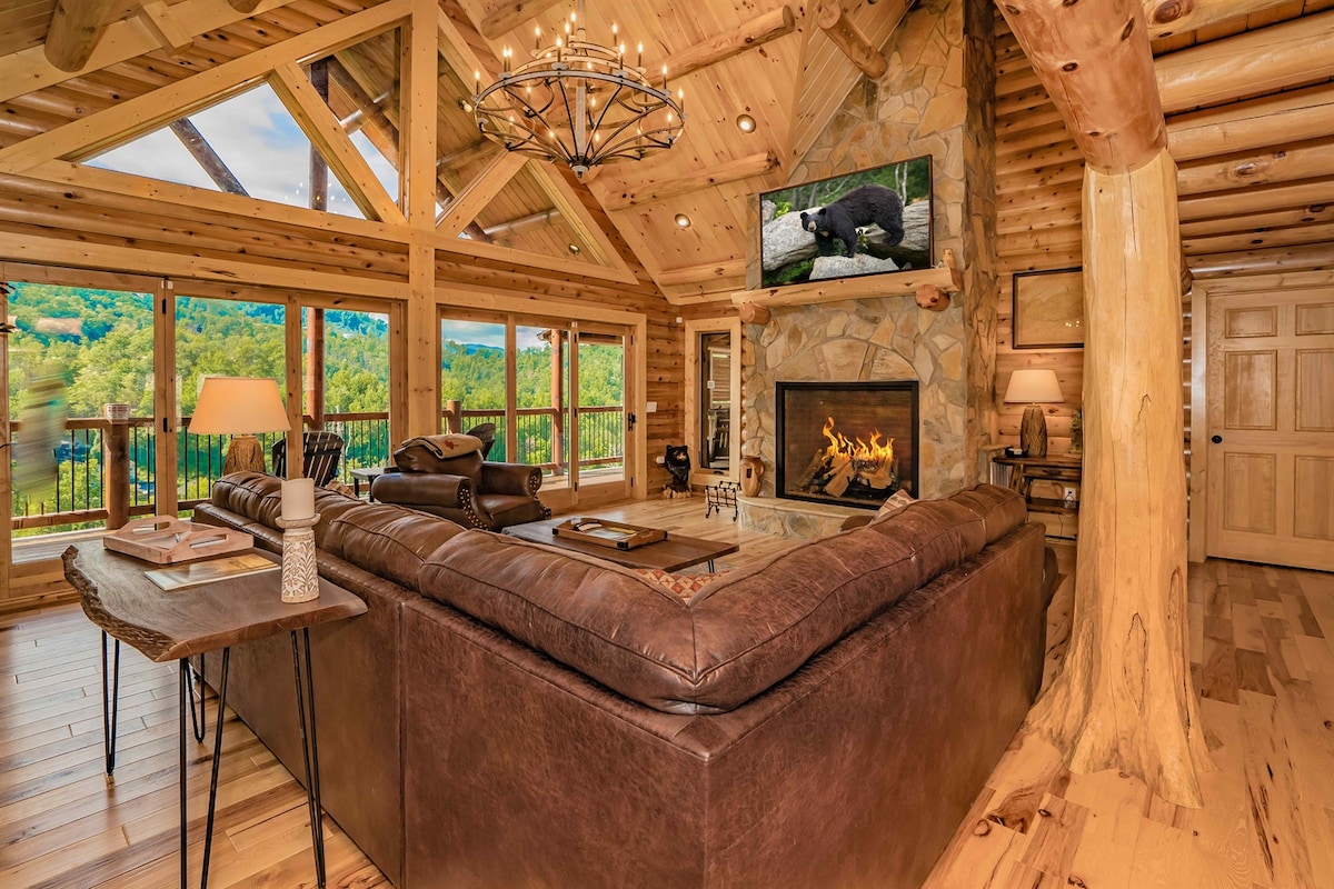 Dnevni boravak na glavnoj razini sa zaobljenim stropovima, plinskim kaminom od kamena i prozorima od poda do stropa s pogledom na planine. Opustite se u udobnim foteljama i uživajte u toplom, otvorenom prostoru koji je izravno povezan s kuhinjom, blagovaonicom i vanjskom terasom.
