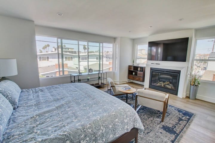 إطلالة رئيسية على غرفة النوم للغرفة. تضيء المدفأة والتلفزيون والنوافذ الغرفة.