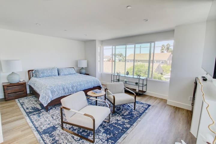 إطلالة رئيسية على غرفة النوم للغرفة. تضيء المدفأة والتلفزيون والنوافذ الغرفة.