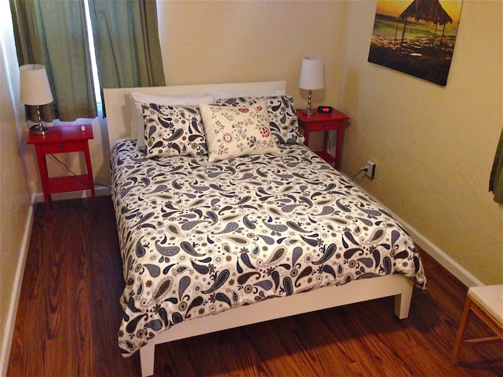 Una cómoda y limpia cama tamaño queen en el dormitorio, todas las sábanas proporcionadas