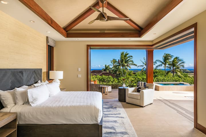 La suite principal se expande al lanai a través de dos paredes de puertas corredizas, mostrando el océano, la terraza de la piscina y las vistas a la montaña.