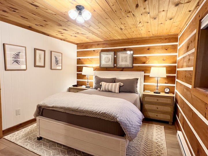 Lower-level Bedroom #2 features a comfy queen bed, closet with hangers & luggage rack, dresser, side chair, and extra blankets. Blackout shades on the window ensure a peaceful, restful night. ️✨