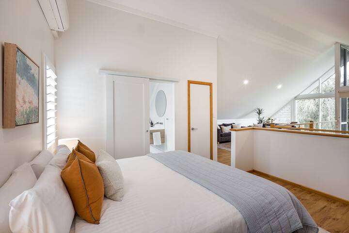 Este elegante dormitorio tipo loft ofrece una espaciosa cama tamaño queen con lujosas almohadas y sábanas elegantes. El diseño de planta abierta se conecta a un moderno baño privado, mientras que los grandes ventanales llenan el espacio con luz natural. ¡Perfecto para un retiro privado!