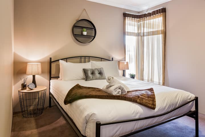 Chumba cha kulala cha malkia kilichopambwa vizuri chenye rangi laini na hifadhi ya kutosha, kinachotoa usingizi wa usiku wenye utulivu.