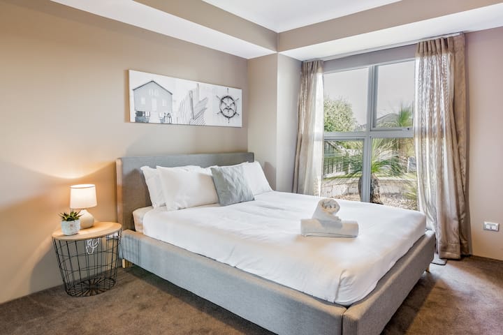 Chumba kingine cha kulala cha starehe cha malkia, kilicho na matandiko ya kifahari na vazi la kuingia.