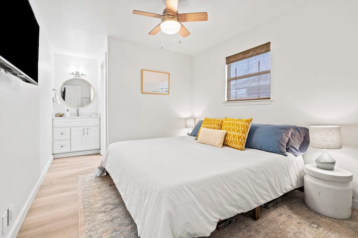 Suite King soleada con almohadas de felpa, baño privado y espacio para relajarse después de los días de playa.