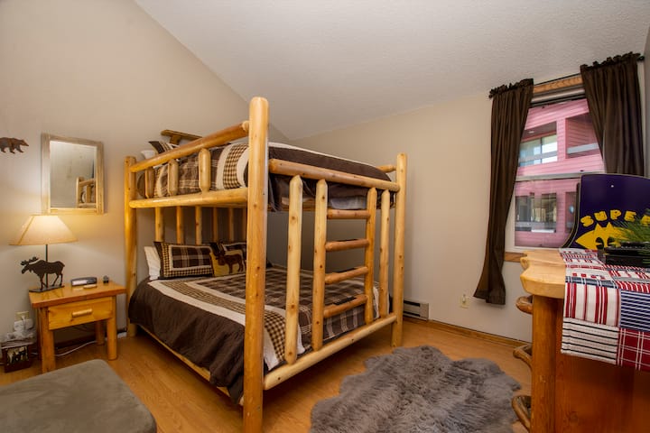 您的舒适乡村卧室配有手工制作的原木双层床和格纹床上用品，为家庭营造完美的山区度假氛围。