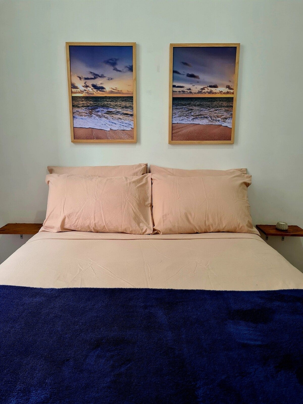 חדר עם מיטה זוגית, חלון עם אור טבעי, מיזוג אוויר, קולבים, אהיל, מאוורר נייד, מעוצב עם מסגרות על הקיר.