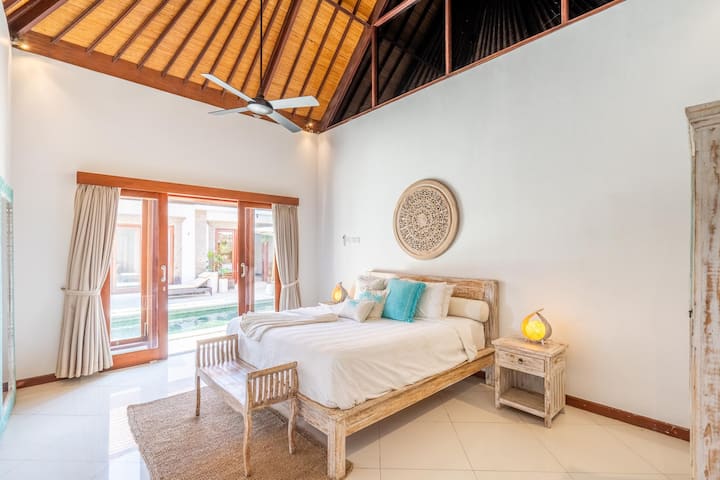 El dormitorio n.º 2 de Villa Jiwa ofrece una lujosa cama tamaño king, un elegante baño privado con bañera y vistas serenas a la resplandeciente piscina.