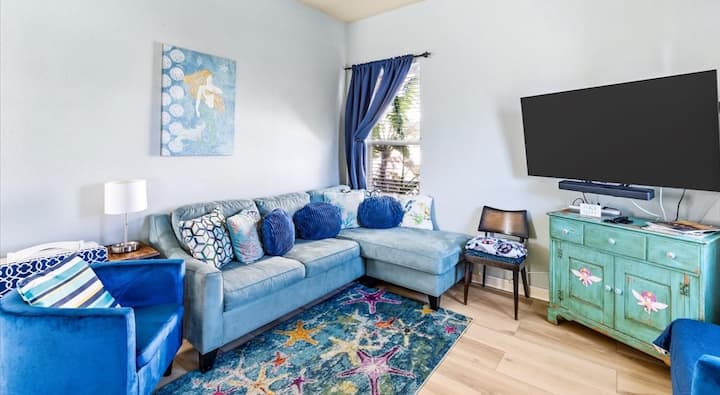 Living room with comfy sectional, big TV, and beachy charm.