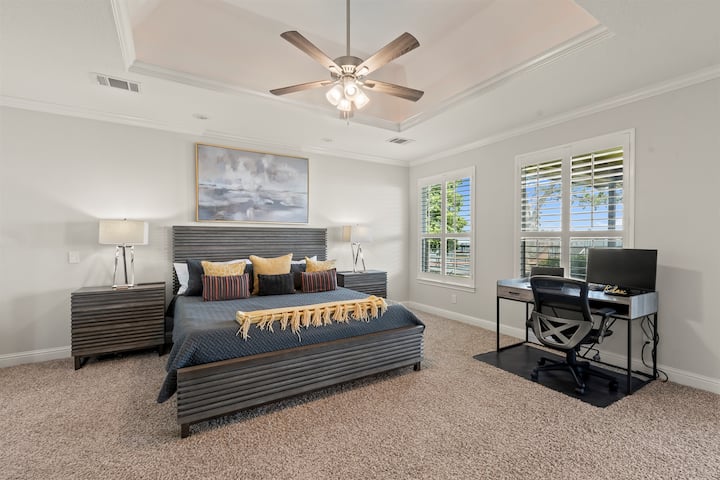 Spacious main bedroom featuring a dedicated workspace with desk and office chair—perfect for remote work, complete with lake views framed by elegant shutters.