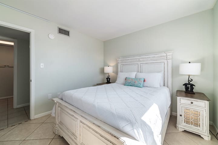 Დედოფლის ზომის კომფორტული საწოლი ხრაშუნა თეთრი თეთრეულით, რომელიც ტუმბოებისა და ლამპების ტუმბოებითაა მოპირკეთებული და მყუდრო და მიმზიდველი სივრცეა.