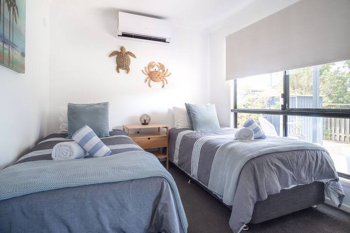 Chambre trois avec deux lits simples et système de climatisation divisé.