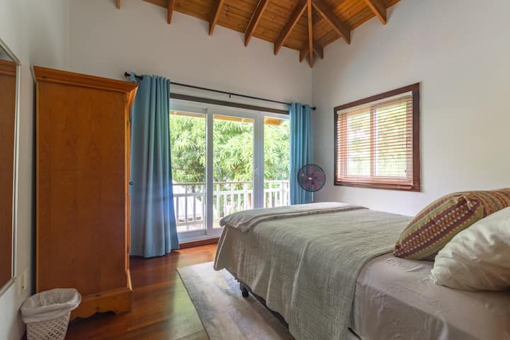 The upstairs guest bedroom features a queen bed and a private balcony, offering incredible views of the pool and ocean.
