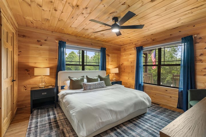 A bright king bedroom with forest views through every window — sleep deep, wake refreshed.