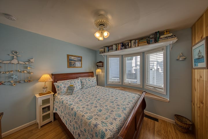 #2 გემის ოთახი ორადგილიანი საწოლით, ფანჯრის სავარძლით, მყარი წიგნებით, კომოდით, ტუმბოებით, საკითხავი ლამპებით, ჭერის ვენტილატორით, სარკითა და კარადით.  #1 სააბაზანოს გვერდით.  Კარადაში არის თამაშები, სამრეცხაო კალათა და საუთოებელი მაგიდა.