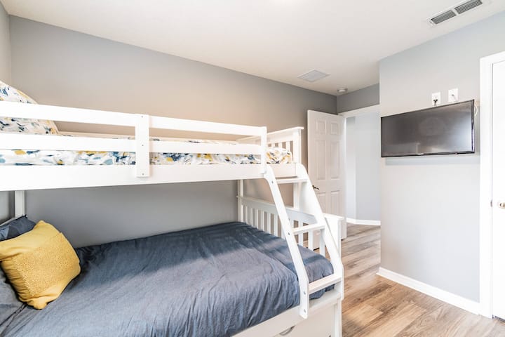 ห้องนอนที่น่าอยู่นี้มีเตียงสองชั้นสีขาวแข็งแรงประดับด้วยเครื่องนอนสีสันสดใสตัดกับผนังสีเทาอ่อน ผ้านวมสีฟ้าเข้มที่อบอุ่นและทีวีติดผนังที่ทันสมัยให้ความบันเทิงสำหรับผู้เข้าพักทุกวัย