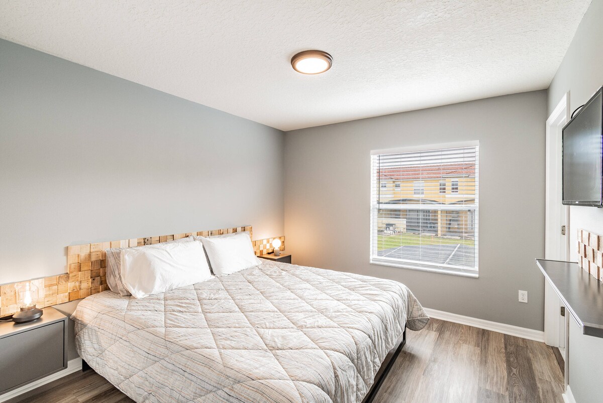 Ova udobna spavaća soba ima prostran, mekan krevet sa stilskim pokrivačem i toplo osvjetljenje pored kreveta za opuštajući ambijent. Veliki prozori propuštaju prirodno svjetlo, ispunjavajući prostor svijetlom i veselom atmosferom za vašu udobnost.