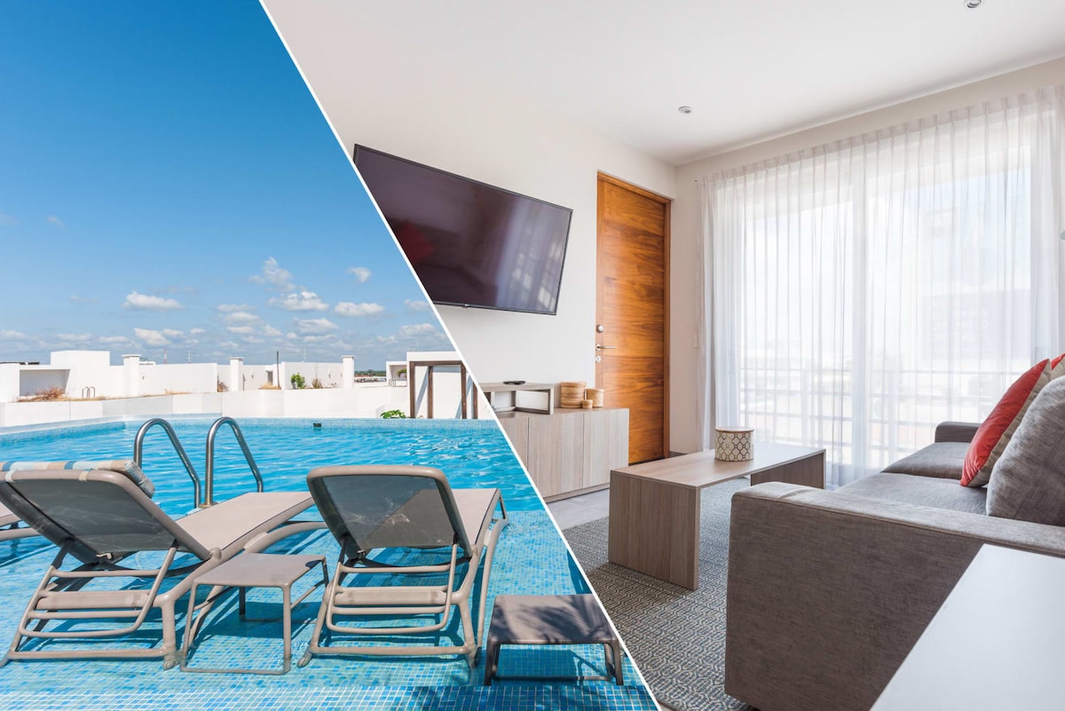 A rooftop space features a bright blue pool, surrounded by lounge chairs. The other side displays a living area with a flat-screen TV mounted on the wall and a door leading outside. Natural light filters through sheer curtains.