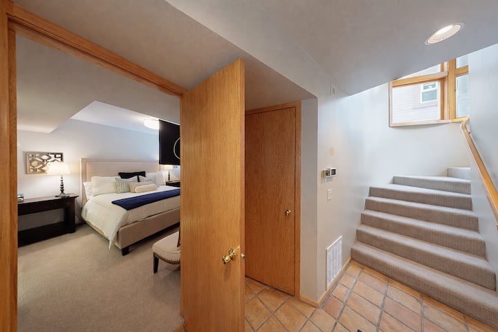 Chumba chako cha kulala chenye starehe kinakusubiri kikiwa na matandiko ya kifahari na vistawishi vya kisasa, huku ngazi zilizofunikwa zikielekeza kwenye mapumziko yako ya faragha ya ghorofani.