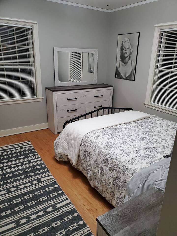 غرفة نوم مع سرير بحجم كوين، وخزانة مع مرآة، وخزانة، ومروحة سقف