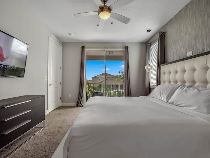 - Брачна спална соба со пристап до балкон и поглед кон градината  
- Ѕиден телевизор и тавански вентилатор за удобност  
- Стилски декор со природна светлина која ја исполнува собата