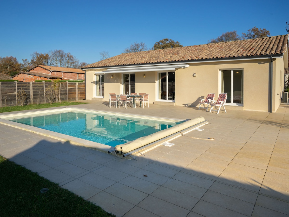 The exterior showcases a private terrace with a swimming pool surrounded by tiled flooring. Lounge chairs are positioned nearby, and a dining table is set for outdoor meals. Large glass doors provide access to the house, allowing natural light to fill the space.