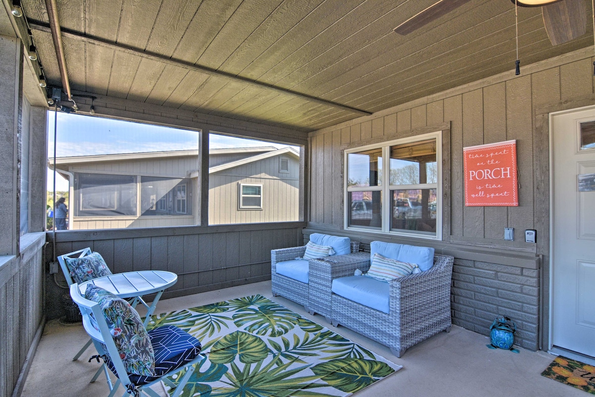 A screened-in porch offers a comfortable seating area with wicker chairs and a small table. A patterned area rug brings color to the space, while large windows allow natural light to fill the room. A ceiling fan is positioned above for added comfort.