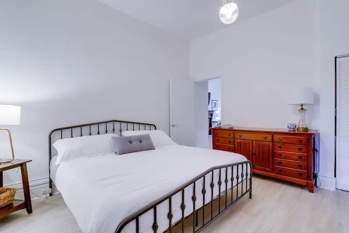 Dormitorio principal con cama tamaño king, cajones de madera, mesa auxiliar y pantallas de lámpara