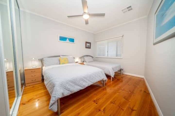 Két hívogató ágy csillogó fapadlón, lágy megvilágítással és tengerparti hangulattal.