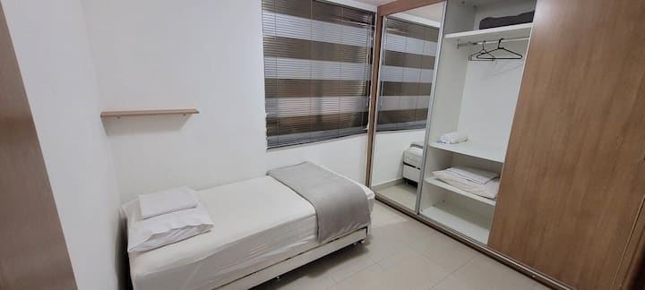 Реверсивна стая в апартамент с двойно легло, завеса, закачалка за дрехи и спално бельо. Този има преносим климатик.