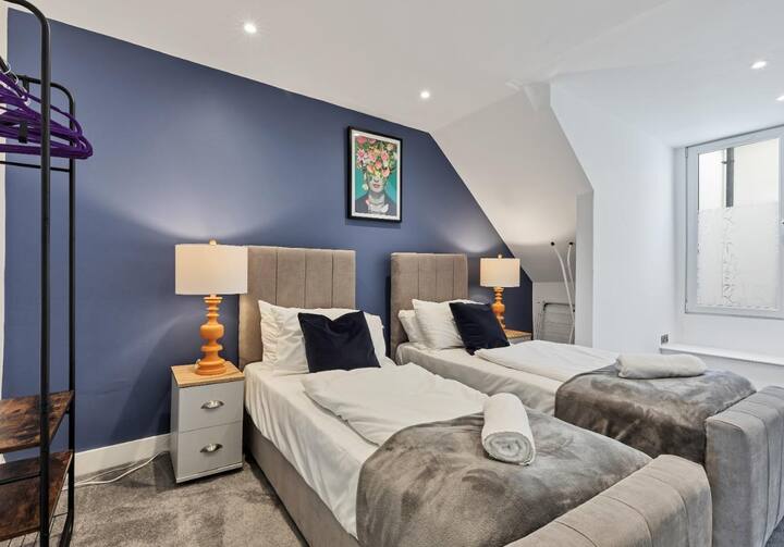 - Entra en este elegante dormitorio con ropa de cama lujosa y una relajante pared de acento azul.
- Las obras de arte modernas y la iluminación acogedora crean un ambiente cálido y acogedor.
- Habitación cuidadosamente diseñada con un espacio para colgar abierto para ropa y toques decorativos elegantes.