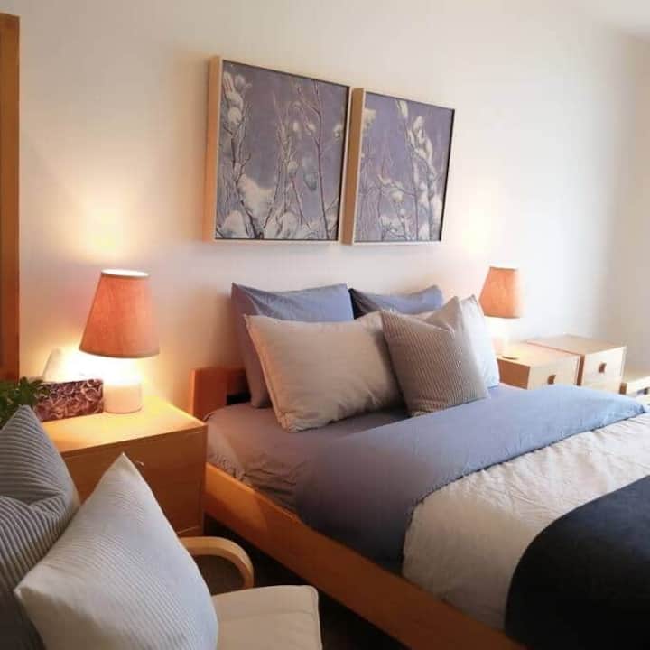 ห้องนอนใหญ่พร้อมเตียงควีนไซส์และประตูระเบียงที่นำไปสู่ริมทะเลสาบ