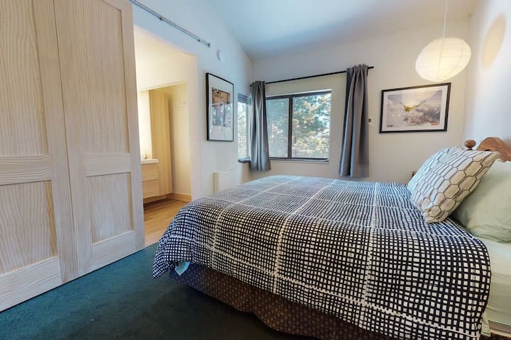 חדר שינה ראשי עם מיטת קינג סייז וחדר רחצה צמוד. נוף ליער מהחלונות הכפולים החדשים עם מסכים חדשים