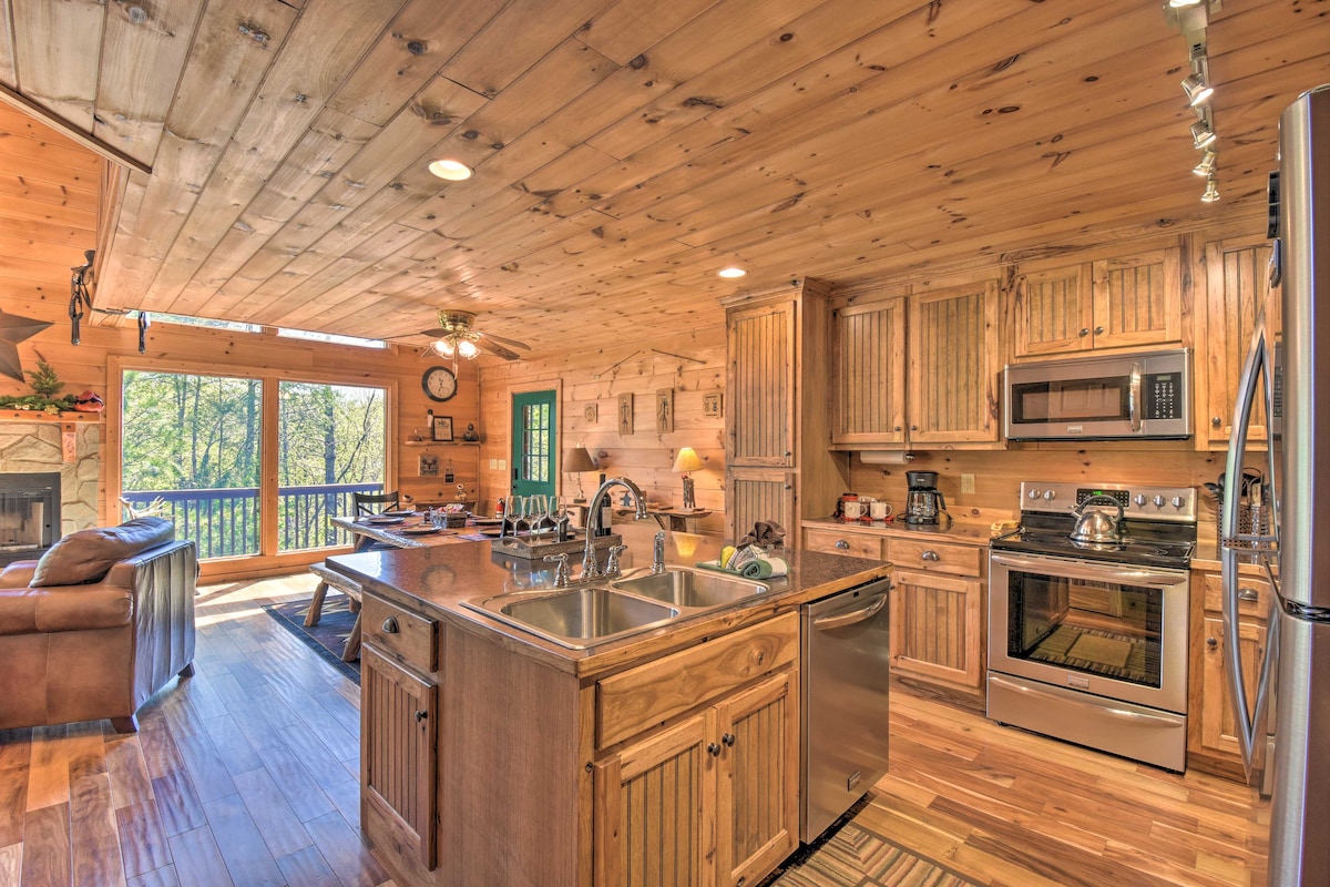 A fully equipped kitchen features wooden cabinetry and stainless steel appliances, including an oven and microwave. An island with sink provides additional prep space, while natural light pours in from large windows, illuminating the dining area and plush seating in the adjacent living space.