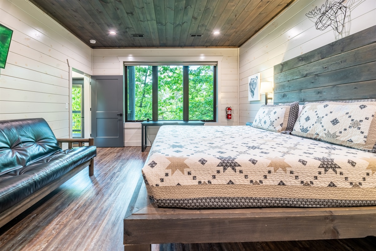 חדר שינה בקומה התחתונה עם מיטת קינג סייז, פוטון, תריסים שחורים, שולחן וחדר רחצה צמוד