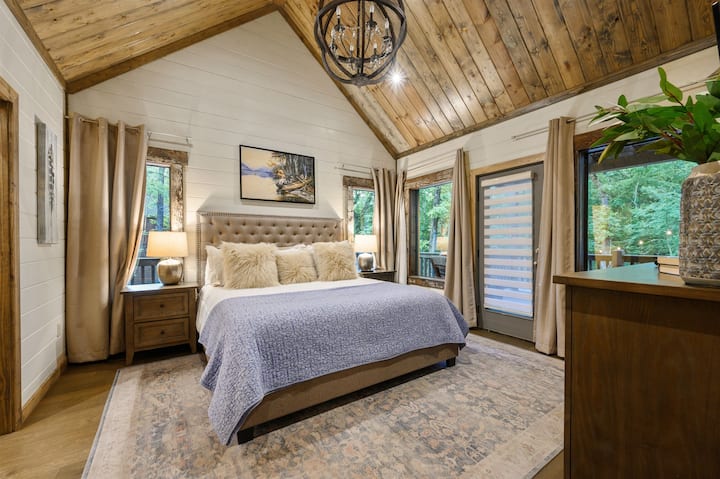 Kitanda cha mfalme, madirisha mengi na ufikiaji rahisi wa eneo la kukaa la ukumbi unakusubiri katika Master Suite 1 chini ya ghorofa. 