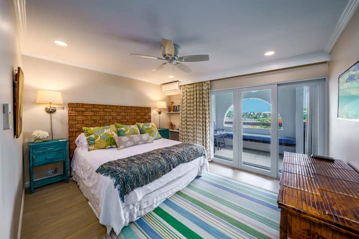 חדר השינה הראשי עם מיטת קינג סייז, חדר רחצה צמוד, מיזוג אוויר קר, טלוויזיה עם מסך שטוח וגישה למרפסת.