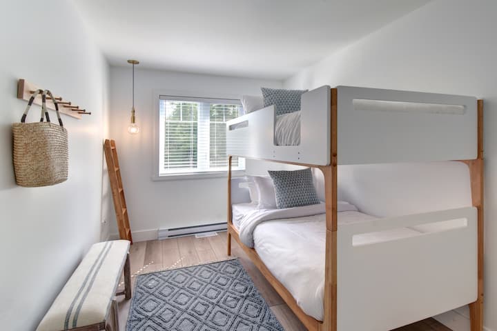 غرفة نوم بيضاء بسيطة مع سرير أنيق بطابقين - مما يزيد من المساحة دون التضحية بالراحة.