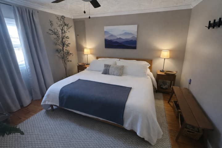 Serene king suite with plush linens, ceiling fan, and warm bedside glow